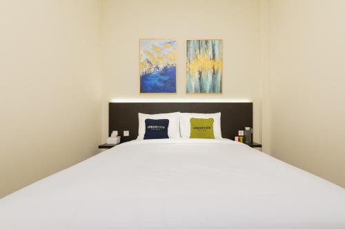 a bedroom with a large white bed with two pillows at Urbanview Hotel Vineyard Cengkareng in Jakarta