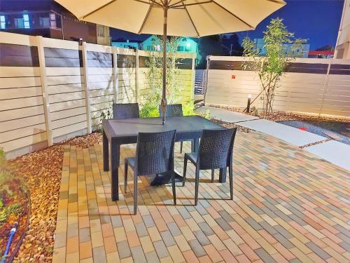 a table with chairs and an umbrella on a patio at 家族連れ等に最適な新築つくばガーデンハウス一棟貸切 in Tsukuba