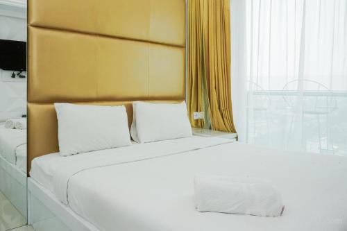 a white bed with two pillows in a room at Comfort and Modern Studio at Tree Park Cikokol Apartment By Travelio in Tangerang