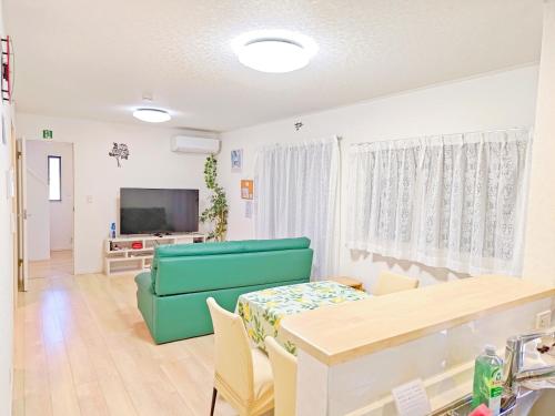 a living room with a green couch and a table at 家族連れ等に最適な新築つくばガーデンハウス一棟貸切 in Tsukuba