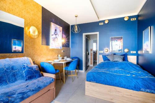 - une chambre avec des murs bleus, un lit et une table dans l'établissement Studio pour 4 - balcon vue mer, à Villeneuve-Loubet