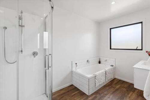 a white bathroom with a tub and a mirror at Stylish & Private near the Lake in Lake Hawea