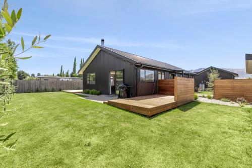 a black house with a large yard with green grass at Stylish & Private near the Lake in Lake Hawea