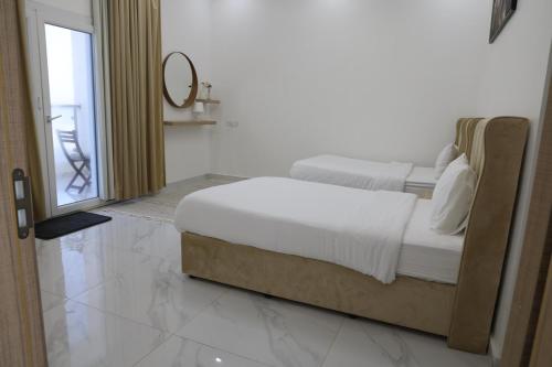 a white bedroom with two beds and a mirror at شالية ماربيا الاشخرة Marbella Ashkhara Chalet in Al Ashkharah