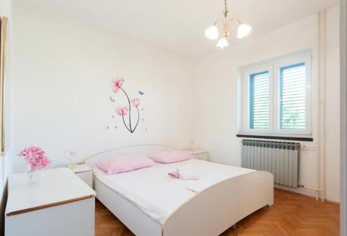 a white bedroom with a bed and two tables at Apartments in Turanj 150 meters from the sea - By TA Leut Agency in Turanj