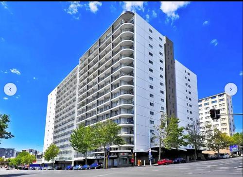 a tall white building on a city street at Auckland city central apartment 2 bedrooms apartment Wi-Fi balcony harbor or skytower view near public parking 1204 in Auckland