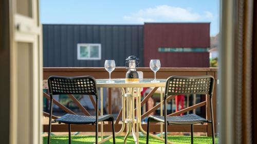 a table with two chairs and wine glasses on a balcony at Daebudo olive Poolvilla pension in Ansan
