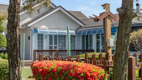 a house with a fence and flowers in front of it at Daebudo olive Poolvilla pension in Ansan