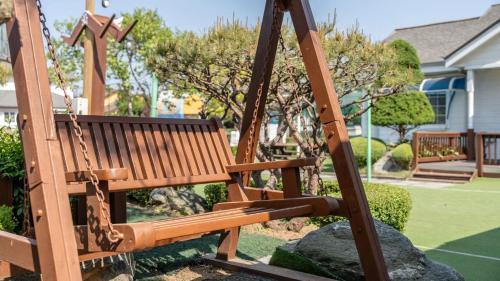 a wooden swing in a playground with a yard at Daebudo olive Poolvilla pension in Ansan