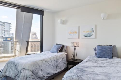 a bedroom with two beds and a large window at Penthouse Apartment Collingwood in Melbourne