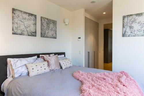 a bedroom with a bed with a pink blanket on it at Penthouse Apartment Collingwood in Melbourne