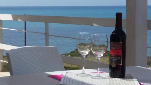 a bottle of wine sitting on a table with two glasses at Vista Mare tra i luoghi di Montalbano in Punta Secca