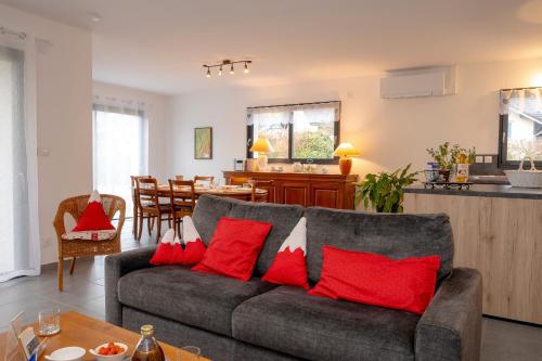 un salon avec un canapé gris avec des coussins rouges dans l'établissement Les Chaudannes, à La Croix-de la Rochette