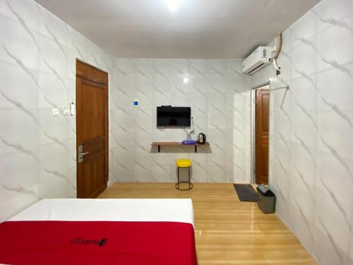 a bedroom with a bed and a tv on a wall at RedDoorz near RSUD Tidar Magelang in Magelang
