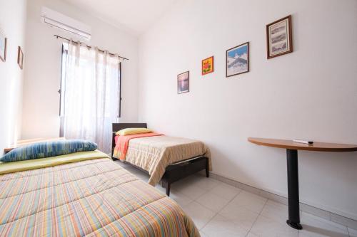a room with two beds and a desk and a table at Casa Via Medici in Milazzo