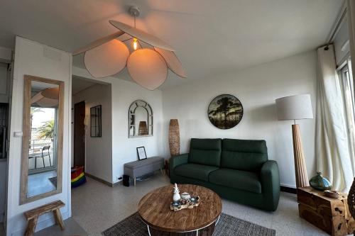 un salon avec un canapé vert et une table dans l'établissement L'Impérial 1- Appartement tout confort 1 chambre Vue mer, au Grau-du-Roi