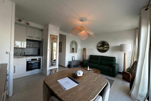 - un salon avec une table et un canapé vert dans l'établissement L'Impérial 1- Appartement tout confort 1 chambre Vue mer, au Grau-du-Roi