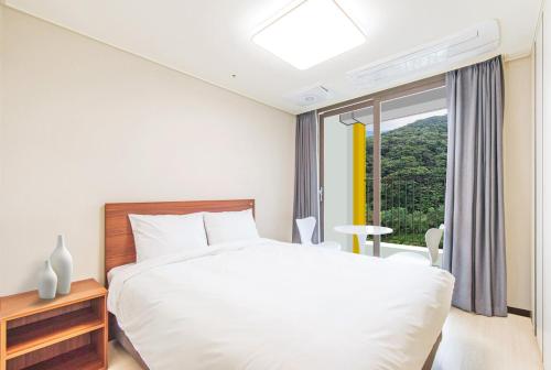 a bedroom with a white bed and a window at Ariari Hotel in Jeongseon