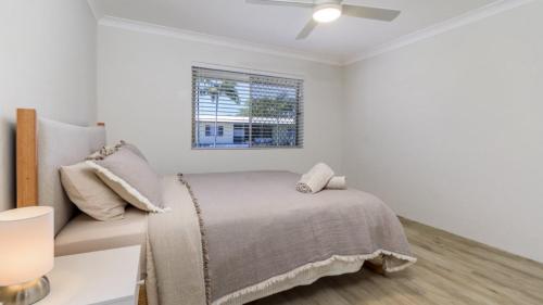 a white bedroom with a bed and a window at 'deja Blue' in Bongaree