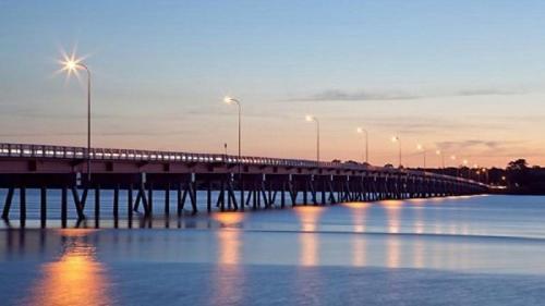 a long pier with lights on it over the water at 'deja Blue' in Bongaree