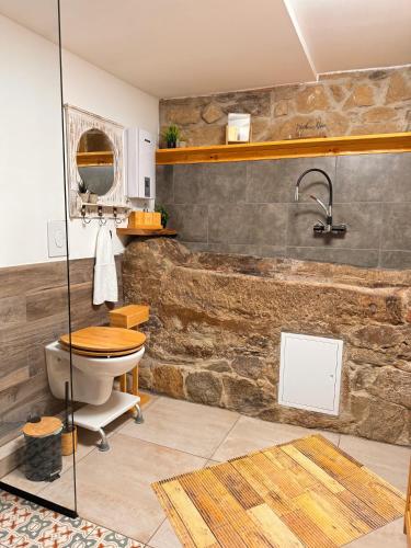 a bathroom with a stone wall with a toilet and a sink at Zum oidn Schmie Haus in Pemfling