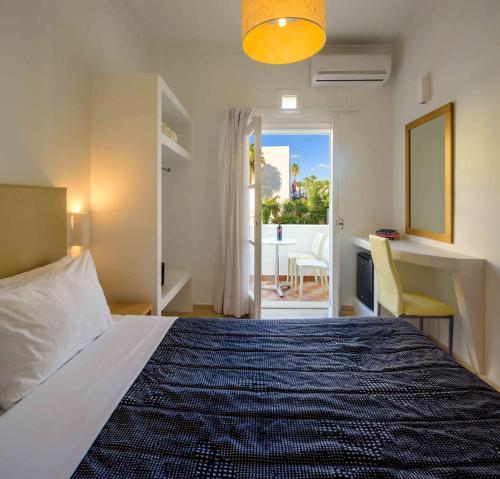 a bedroom with a bed with a view of a patio at Afroditi Venus Beach Resort in Kamari