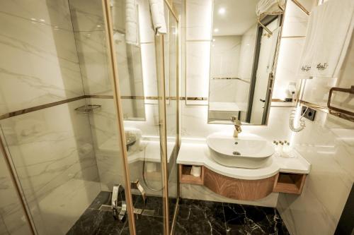 a white bathroom with a sink and a shower at Leaf Port Hotel in Antalya
