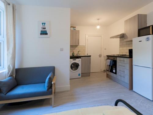 a living room with a blue couch in a kitchen at Studio flat in Heart of Southend - Pass the Keys in Southend-on-Sea