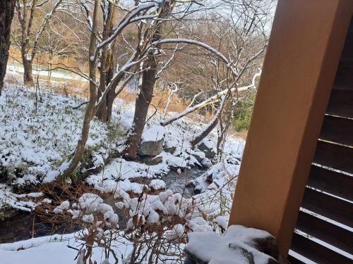 a winter view of a creek with snow on the ground at ローズウッドガーデンアンドヴィラ in Nasu