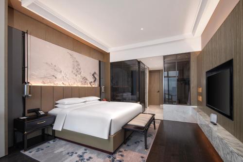 a bedroom with a large bed and a tv at Sofitel Hangzhou Yingguan-Olympic Center Hotel in Hangzhou