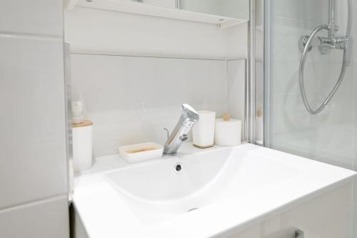 une salle de bain blanche avec un lavabo et une douche dans l'établissement Appartement cozy - Proche métro, à Saint-Denis