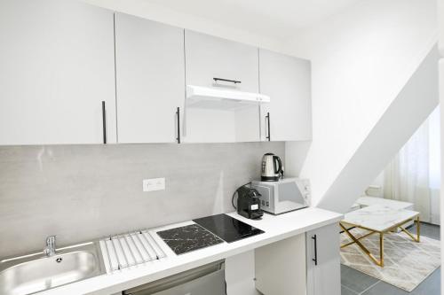 une cuisine blanche avec un évier et un micro-ondes dans l'établissement Appartement cozy - Proche métro, à Saint-Denis