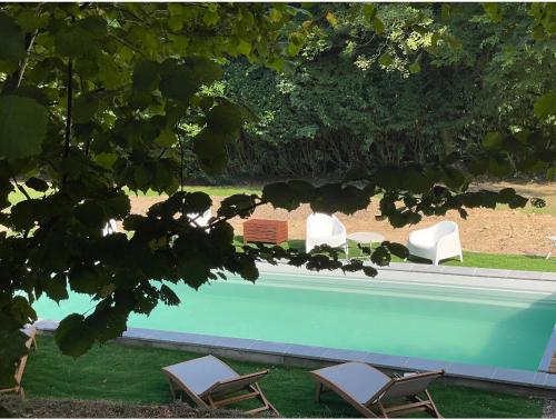 2 chaises longues et une piscine sur gazon dans l'établissement Campagne bohème chic & Piscine Privée à Honfleur, à Équemauville