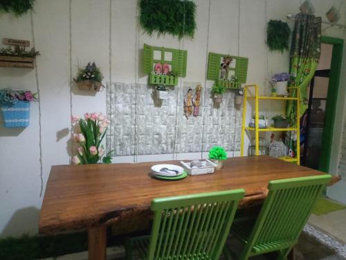 a wooden table with two green chairs in a room at GS Homestay Banyuwangi in Banyuwangi