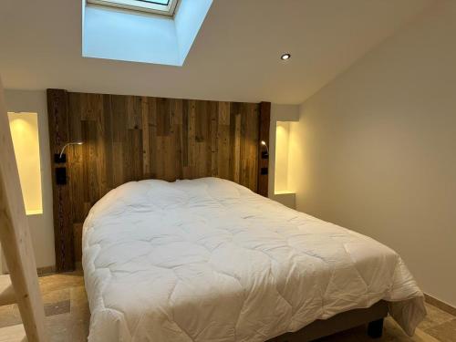 une chambre avec un lit blanc avec une lucarne dans l'établissement Odalys Chalet L'Arpette Lodge, à La Plagne Tarentaise