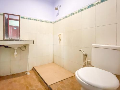 a bathroom with a toilet and a window and a sink at Surya Guest House Urbanview Probolinggo in Kanigaran