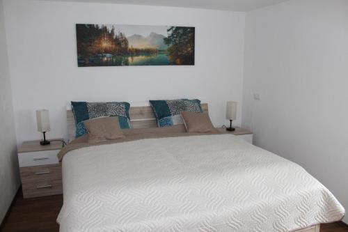 a bedroom with a white bed with a painting on the wall at Ferienwohnung Jolie in Sankt Oswald