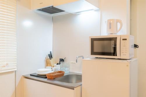 a kitchen with a microwave on top of a refrigerator at 301奈良難波に便利な静かで快適マンション in Higashi-osaka