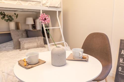 a table with two cups and a vase with a flower on it at 301奈良難波に便利な静かで快適マンション in Higashi-osaka