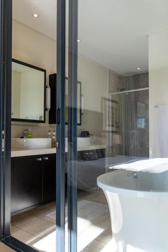 a bathroom with a tub and two sinks and a bath tub at Skyline Serenity - Knightsbridge in Cape Town