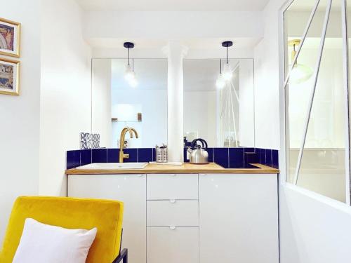 une cuisine avec des placards blancs et une chaise jaune dans l'établissement Superbe appartement a Paris - FLAT-GUEST, à Paris