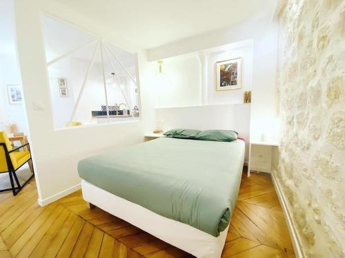 une chambre avec un lit dans une pièce blanche dans l'établissement Superbe appartement a Paris - FLAT-GUEST, à Paris