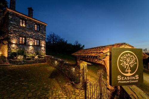 a sign in front of a stone building with a house at 4 Seasons Premium Chalet & Massage Treatments in Palaios Agios Athanasios
