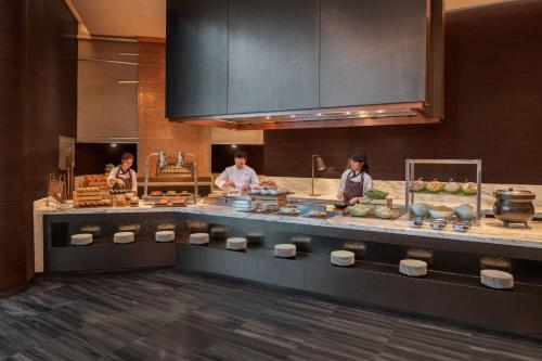 three people in a kitchen preparing food in a kitchen at Le Meridien Bangkok in Bangkok