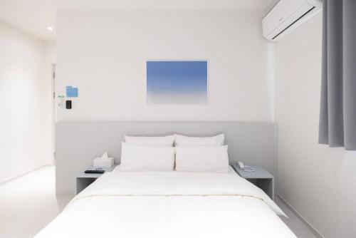 a white bedroom with a white bed and a white wall at 은행 아늑에어 대전역점 Aank Air Hotel Daejeon Station in Daejeon