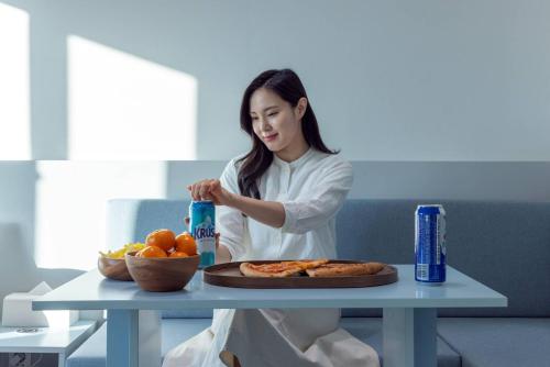 a woman sitting at a table with a plate of food at 은행 아늑에어 대전역점 Aank Air Hotel Daejeon Station in Daejeon