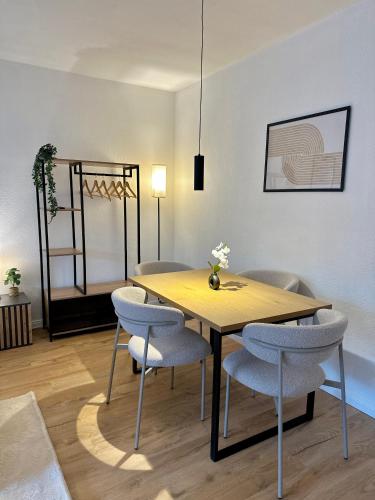 a dining room with a wooden table and chairs at Moderne 2-Zimmer-Whg - Nähe Bahnhof mit Balkon und Stellplatz - 2 Smart-TV in Norderstedt