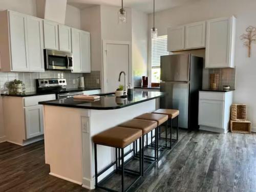 a kitchen with white cabinets and a large island with bar stools at Peaceful Vacation Spot with Modern Touches and Amazing Ambiance in Leander
