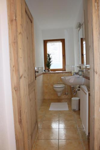 a bathroom with a wooden door and a sink and a toilet at Apartments Wiglhof in Jenbach
