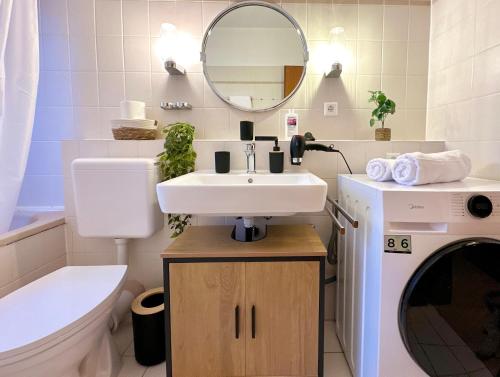 a bathroom with a sink and a toilet and a mirror at Moderne 2-Zimmer-Whg - Nähe Bahnhof mit Balkon und Stellplatz - 2 Smart-TV in Norderstedt